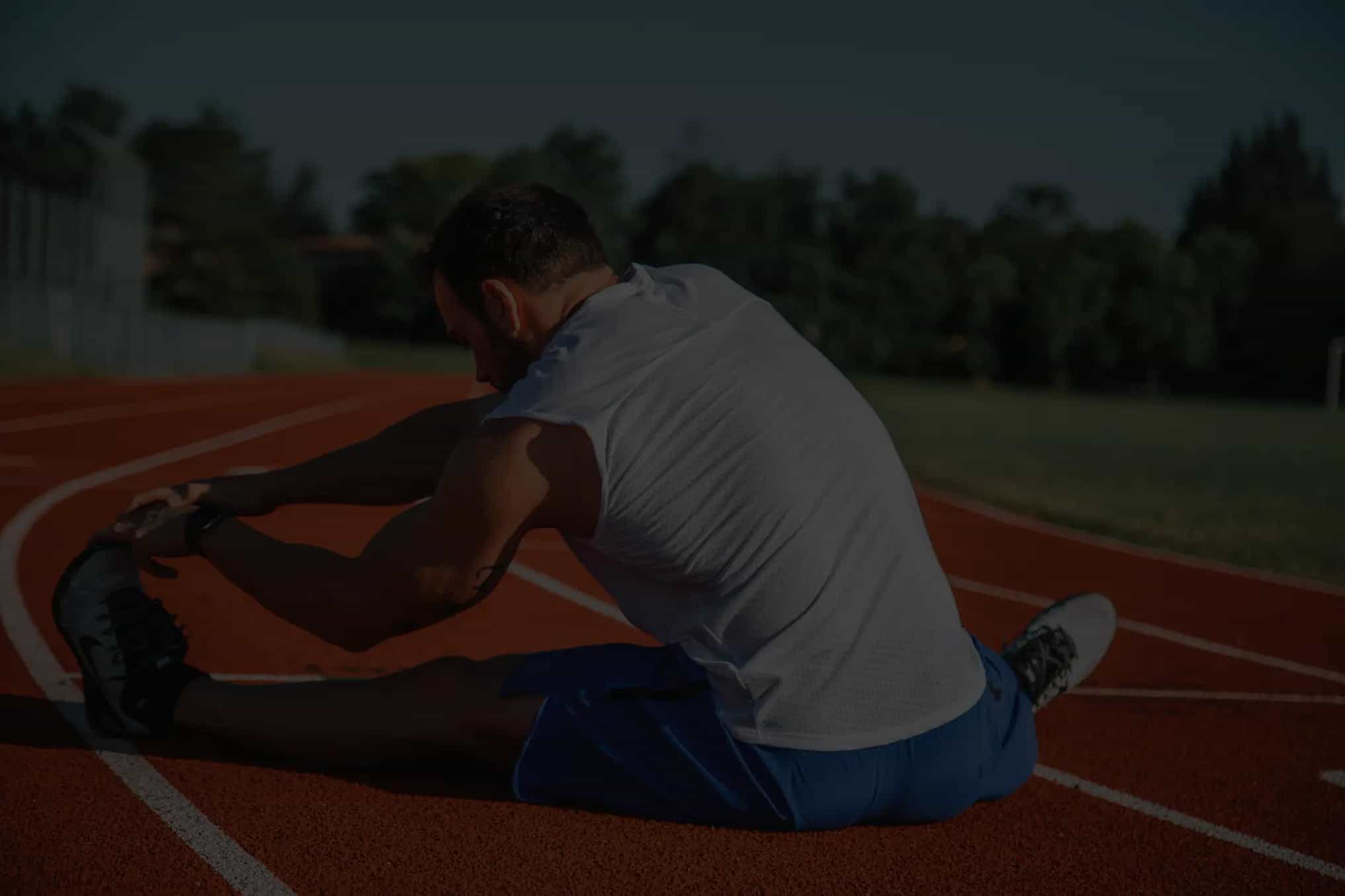 A man on a race track doing stretched